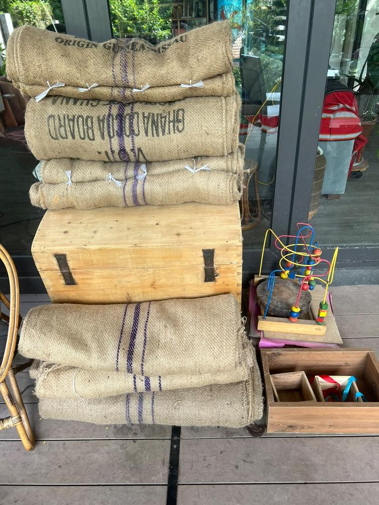 Repurposed burlap coffee and cocoa sacks stacked on a wooden crate, ready to be reused as natural building materials