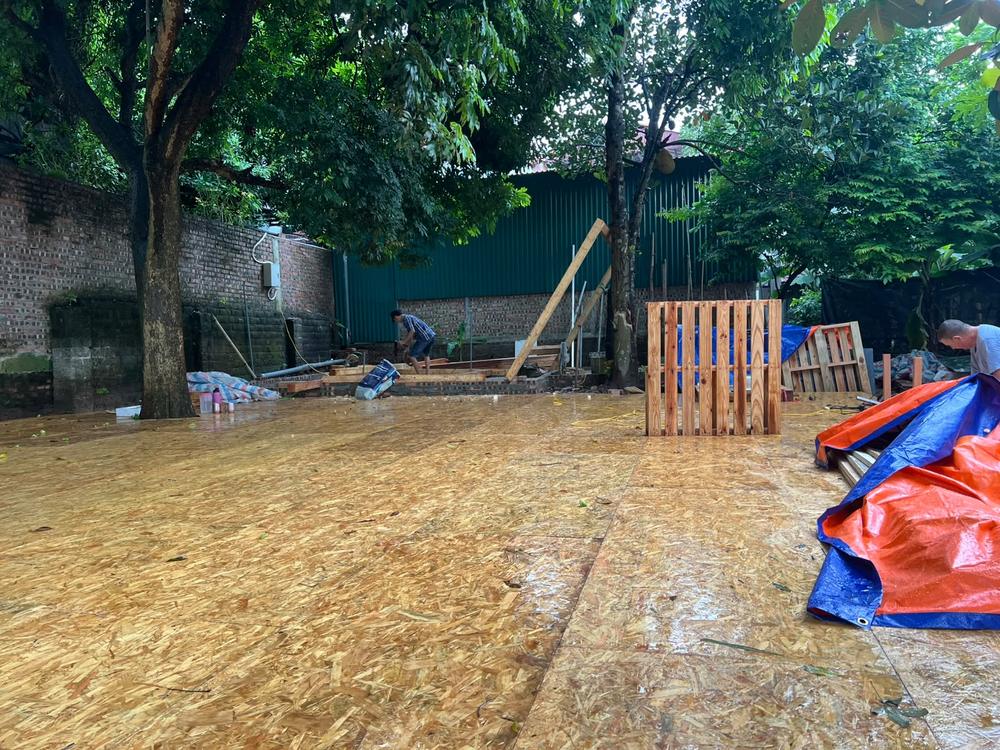 OSB flooring laid down on site, with reclaimed pallets and building materials sheltered under a tarp
